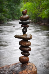 stones balanced on top of each other next to a flowing river