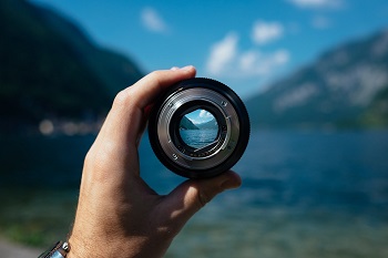 hand holding up a lens with fjord backdrop