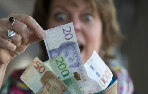 woman is excited as she pulls out a 20-crown bill from a larger pile.