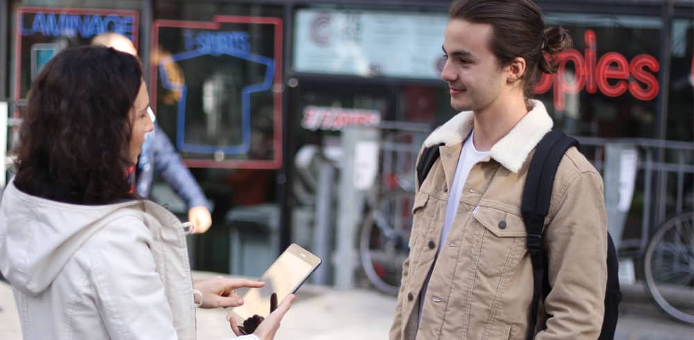 a woman interviews a man in the street to understand his customer requirements.